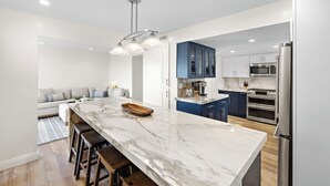 Una cocina moderna con una isla de mármol, electrodomésticos de acero inoxidable y armarios azules.