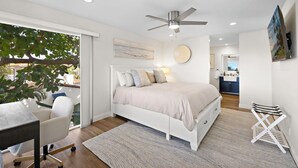 Un dormitorio moderno con cama, ventilador de techo, escritorio y silla.