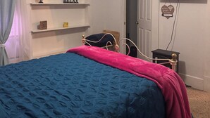 Een slaapkamer met een bed, een plafondventilator, een televisie en een deur.