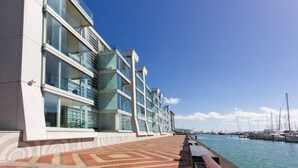A waterfront hotel with a modern design, featuring a patterned walkway and a marina with boats in the background. - Waterfront Marina Retreat – Pool, Gym & Parking (Auckland City)