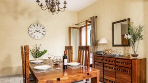 A dining area with a wooden table set for four, a clock on the wall, and a mirror above the table.
