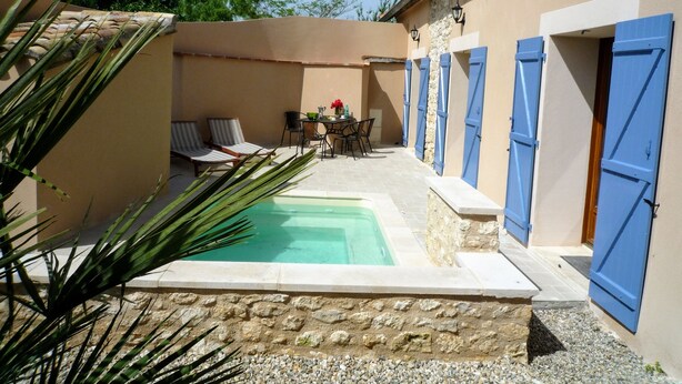 A courtyard with a pool, seating area, and a table with chairs.