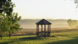 A gazebo in a grassy field with trees in the background.
