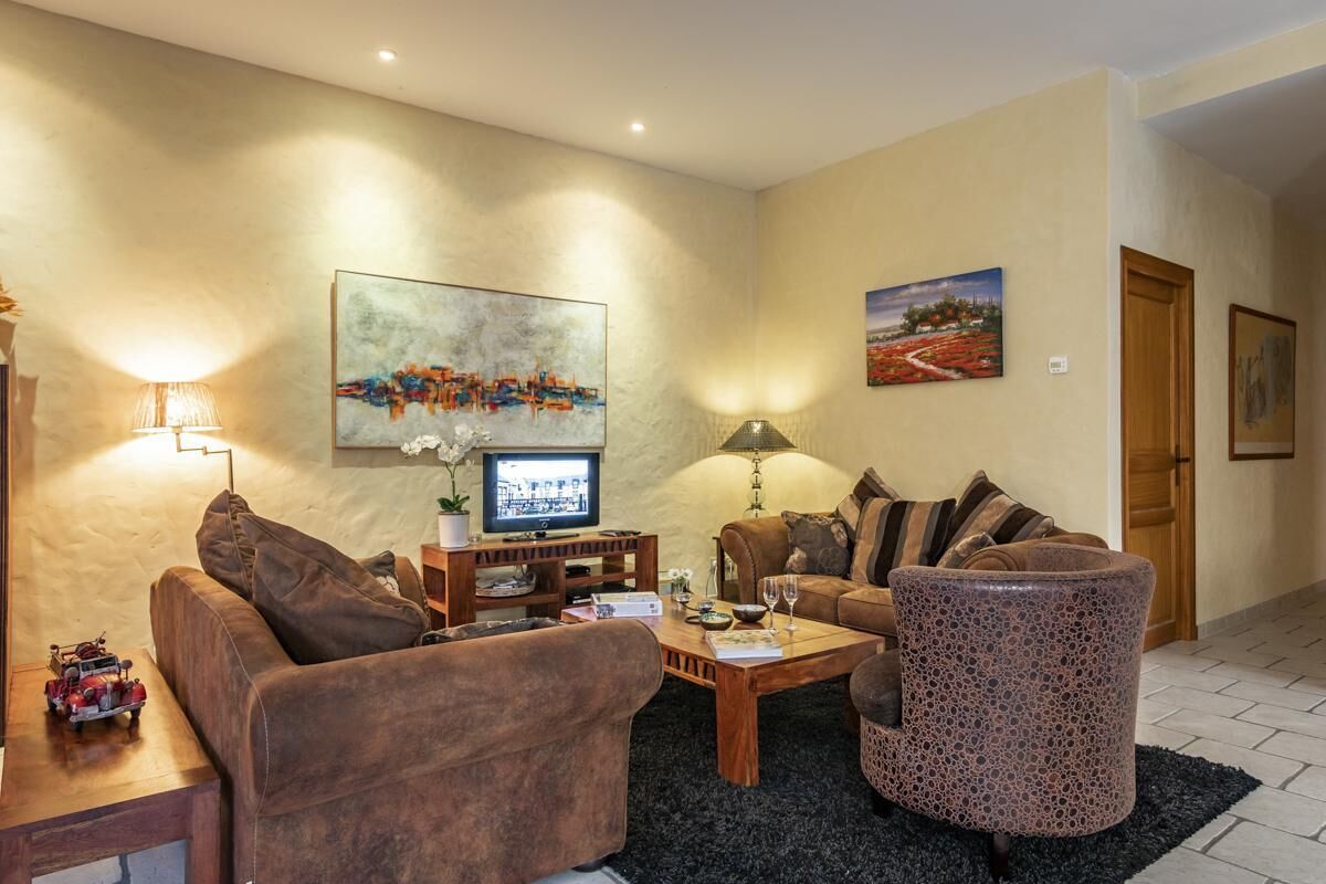 A living room with a sofa, armchair, coffee table, and a television.