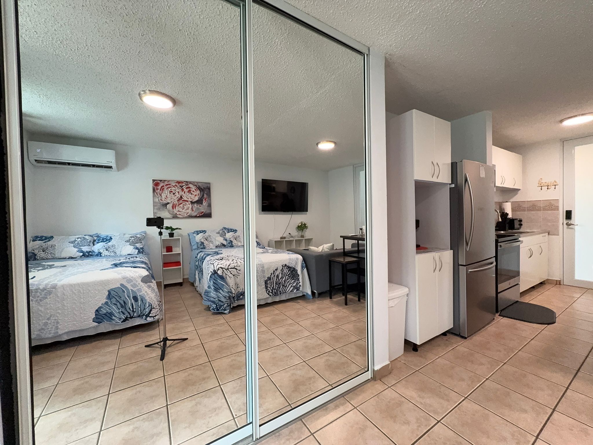 Un apartamento moderno con pared espejada, dos dormitorios, una cocina y un comedor.