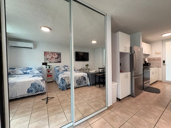 A modern apartment with a mirrored wall, two bedrooms, a kitchen, and a dining area.