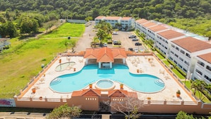 A hotel with a large swimming pool, multiple buildings, and surrounding greenery. - Golden Dream Studio 2nd floor B (Isabela)