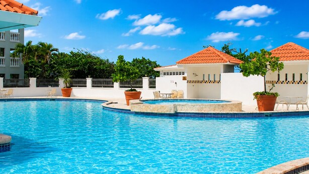 A swimming pool with a tiled edge, surrounded by lounge chairs and potted plants. - Golden Dream Studio 2nd floor B (Isabela)