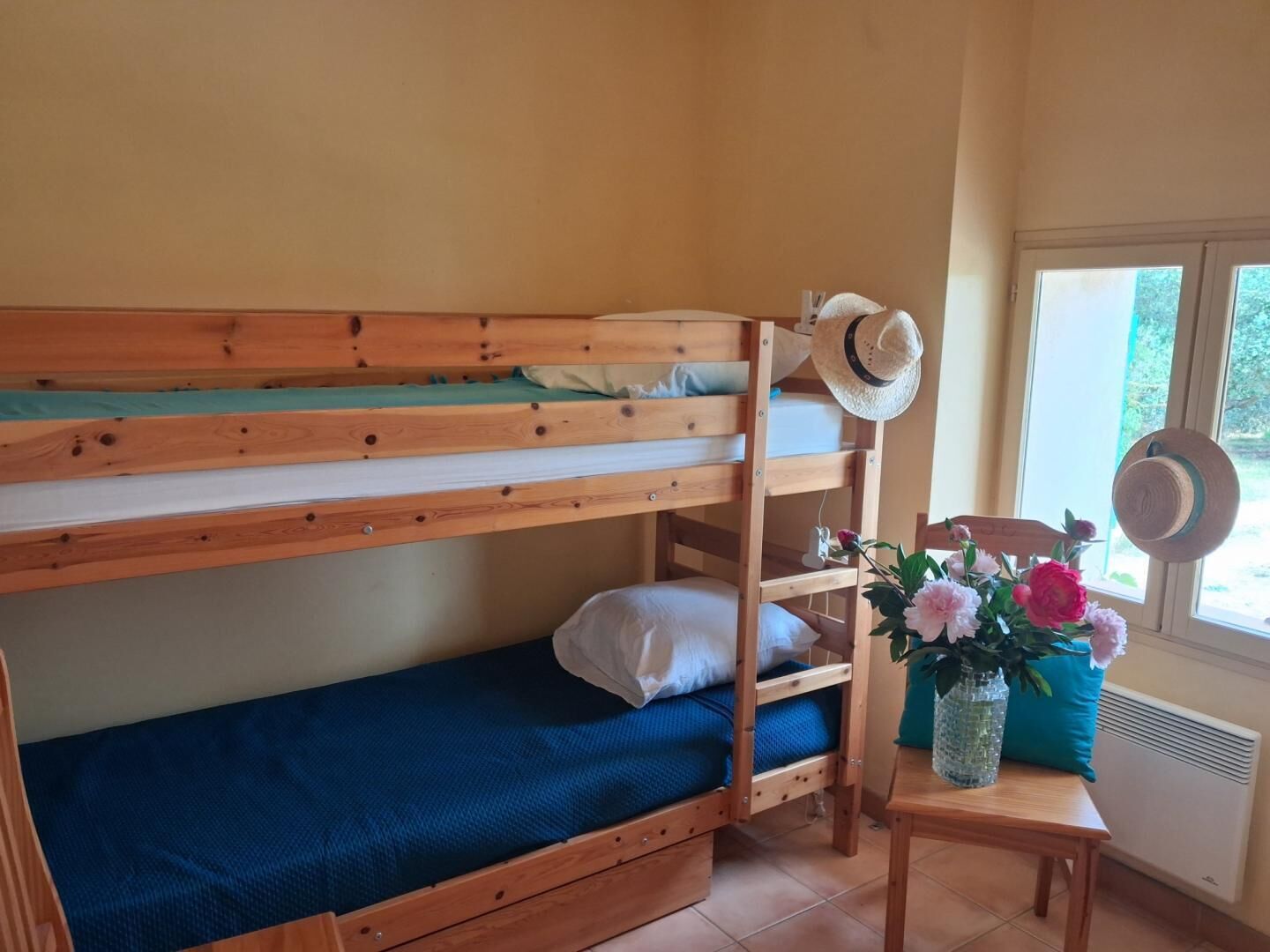 A bunk bed with a hat and flowers on a table.