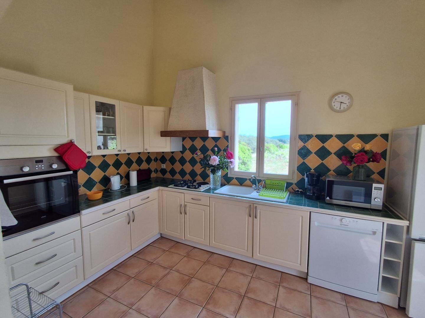 Une cuisine avec des meubles blancs, une cuisinière, un four à micro-ondes et une fenêtre donnant sur un beau paysage.