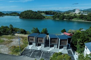 Una propiedad frente al agua con estacionamiento, un edificio de techo rojo y una gran masa de agua.