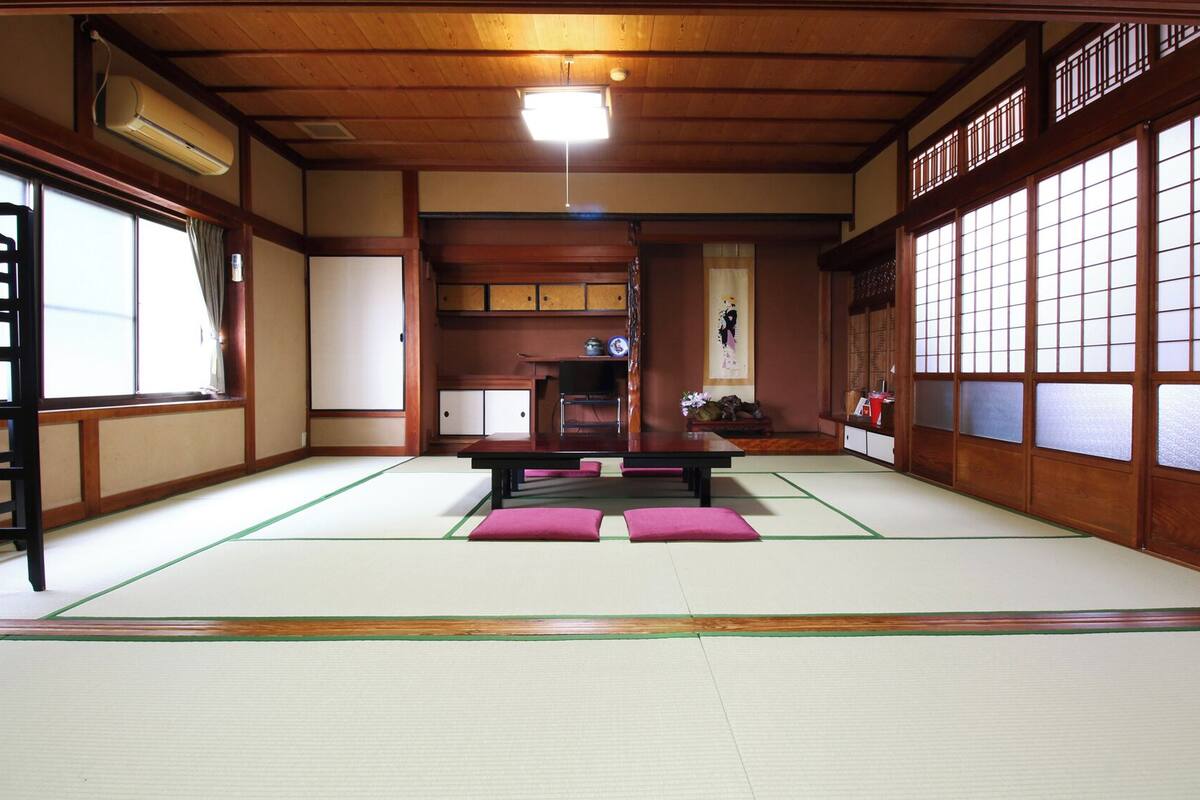 A traditional Japanese room with tatami flooring, a low table, and sliding doors.