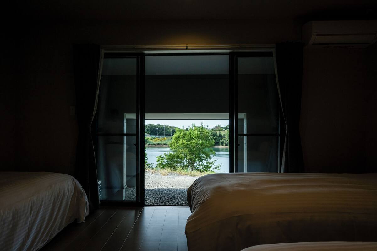 A bedroom with a large sliding glass door leading to a lake view.