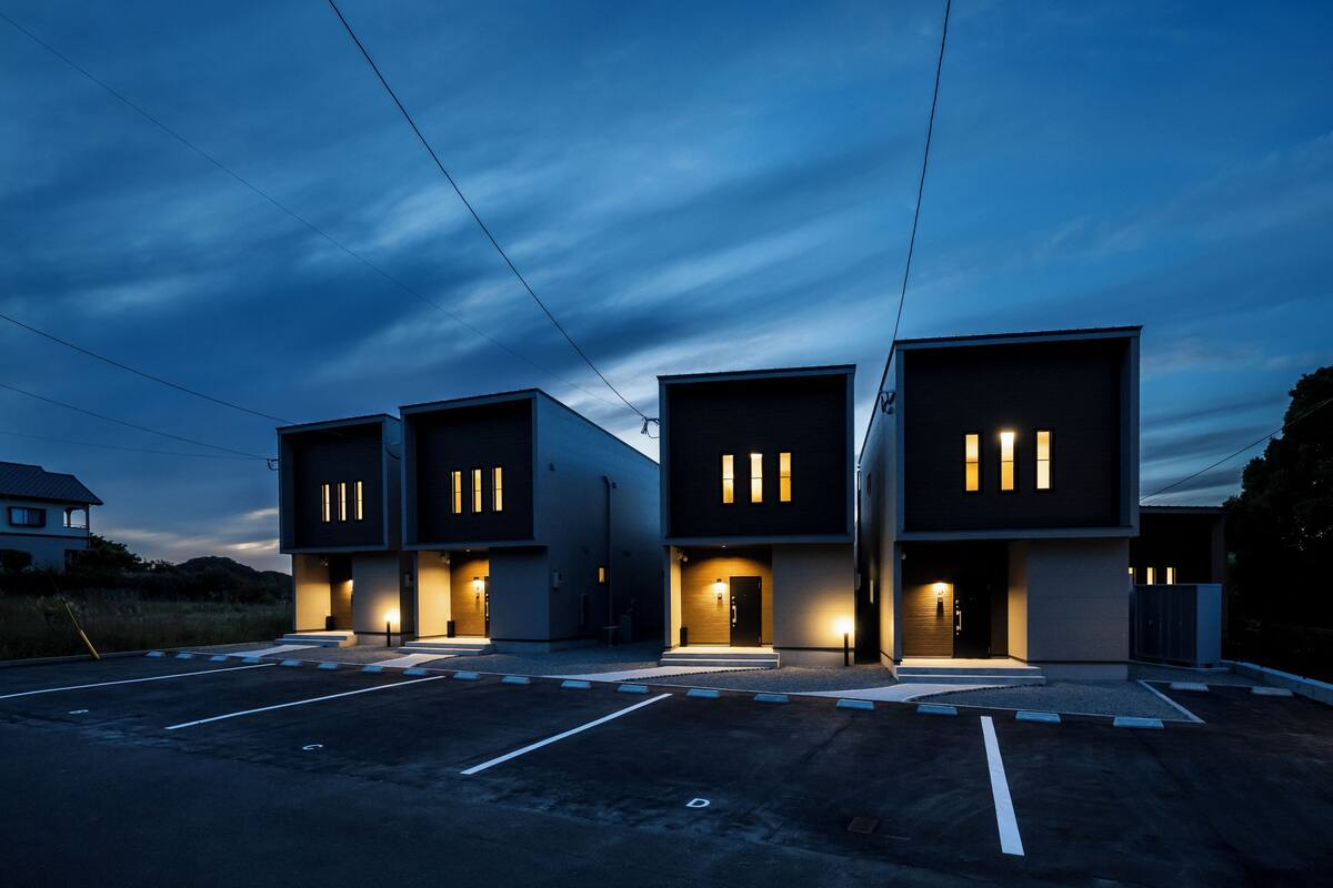 A modern building with multiple entryways and illuminated windows at dusk.