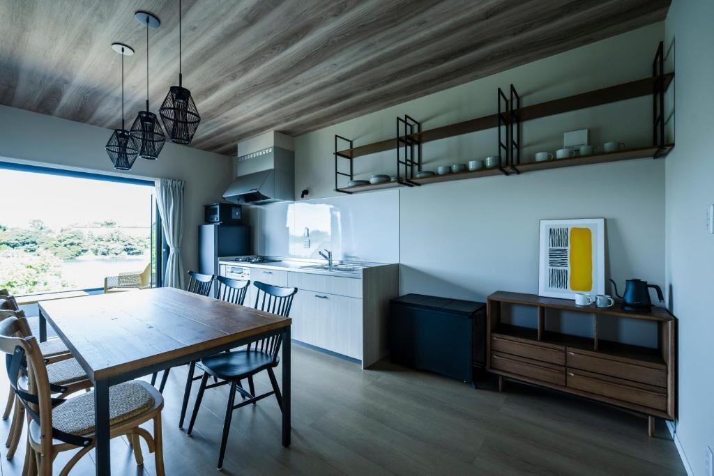 Una cucina moderna con soffitto in legno, scaffali integrati e un'area pranzo con tavolo e sedie in legno.