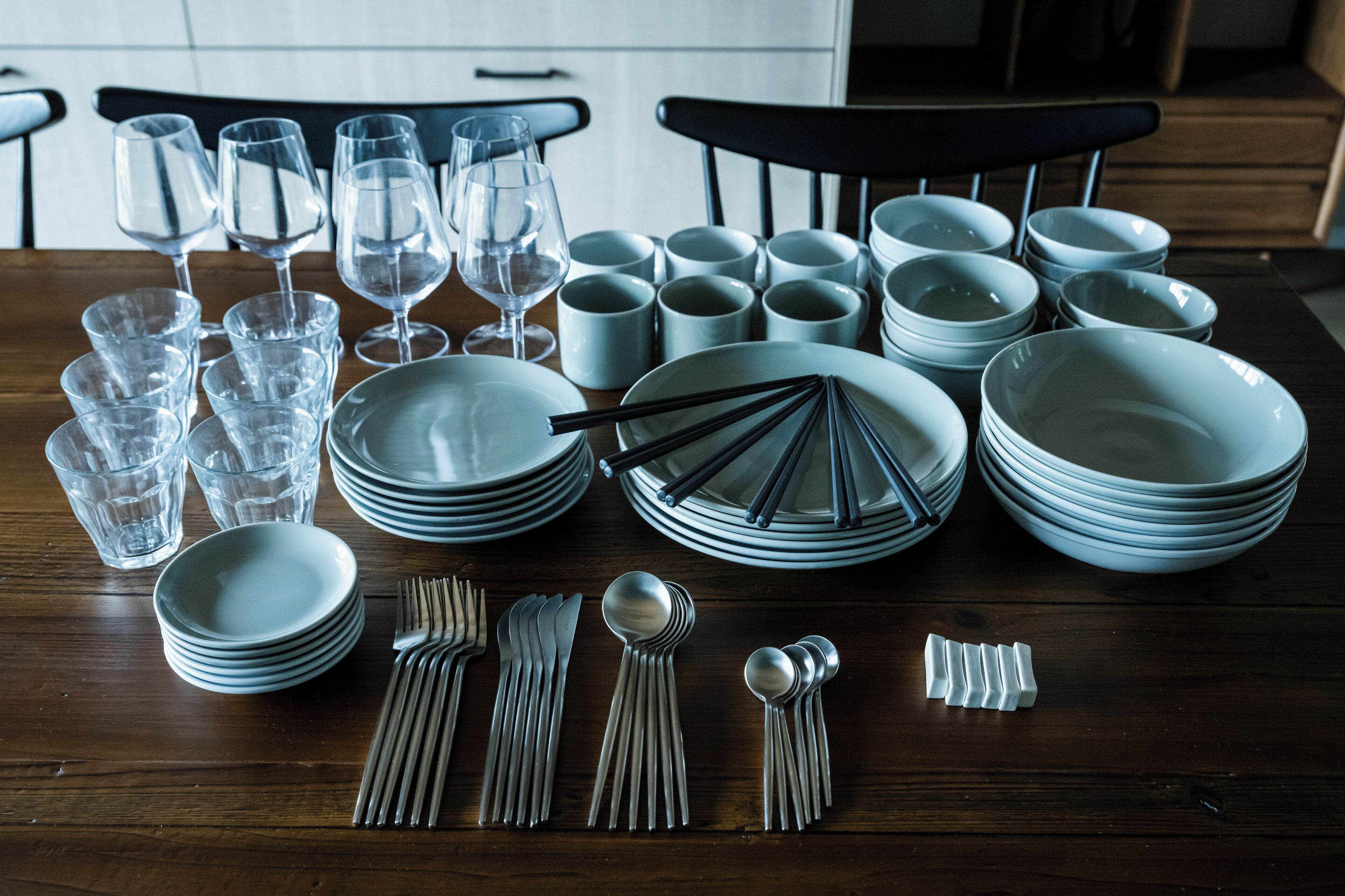A dining table set with multiple plates, bowls, glasses, and cutlery.