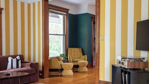 A living room with a sofa, armchair, ottoman, and a record player. - The Wunderhaus – 4BR Minneapolis Escape (Minneapolis)