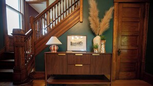 A wooden staircase, a console table with a lamp, a framed picture, and a vase with pampas grass. - The Wunderhaus – 4BR Minneapolis Escape (Minneapolis)