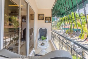 A balcony with a glass door, a small table with a plant, and a chair. - Luxurious 3 bedroom apartment 15 minutes from the airport (Santo Domingo Este)