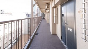 A corridor with a metal railing, a patterned floor, and a door with a lock. - b&Shin-Osaka (Osaka)