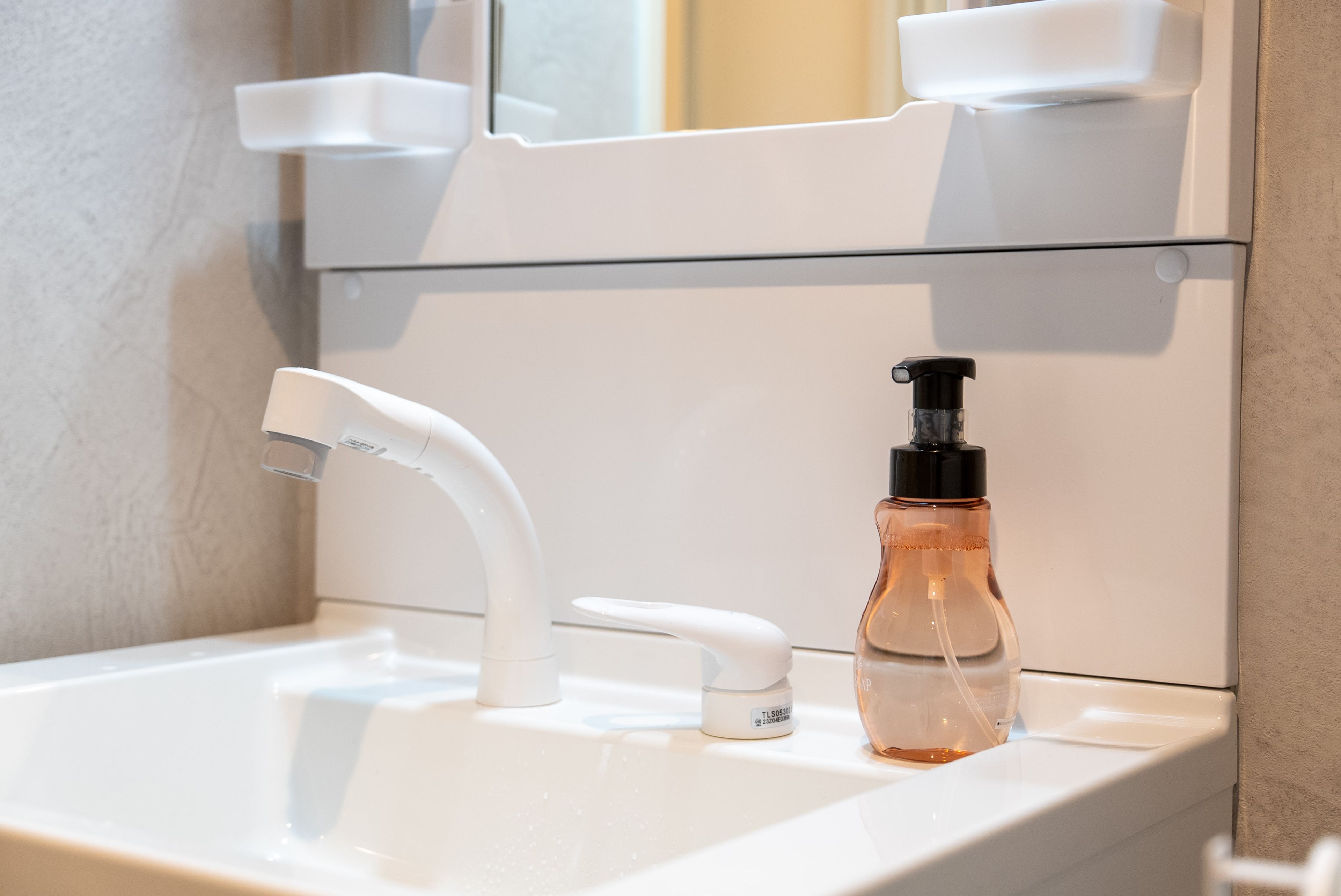 A bathroom sink with a white faucet and a clear soap dispenser.
