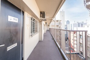 A corridor with a metal railing, a door labeled '910', and a view of the cityscape in the background. - b&Shin-Osaka (Osaka)