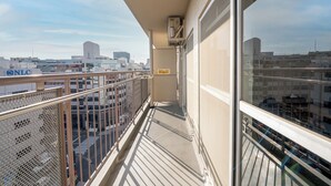 A balcony with a view of the cityscape, including a building with a sign that reads "NLC". - b&Shin-Osaka (Osaka)