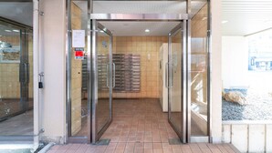 A hotel entrance with a glass door, tiled floor, and a visible elevator. - b&Shin-Osaka (Osaka)