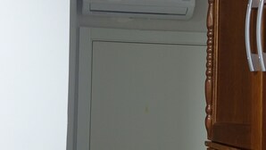 A closed door with a keyhole, a white air conditioning unit above it, and a wooden cabinet to the right. - Fully furnished apartment (Rio do Sul)