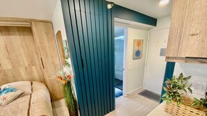 Une chambre moderne avec un lit, une tête de lit en bois, une cloison bleue et un petit balcon avec vue.