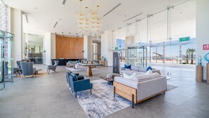 Eine großzügige Lobby mit Empfangsschalter, Sitzgelegenheiten und Blick ins Freie.