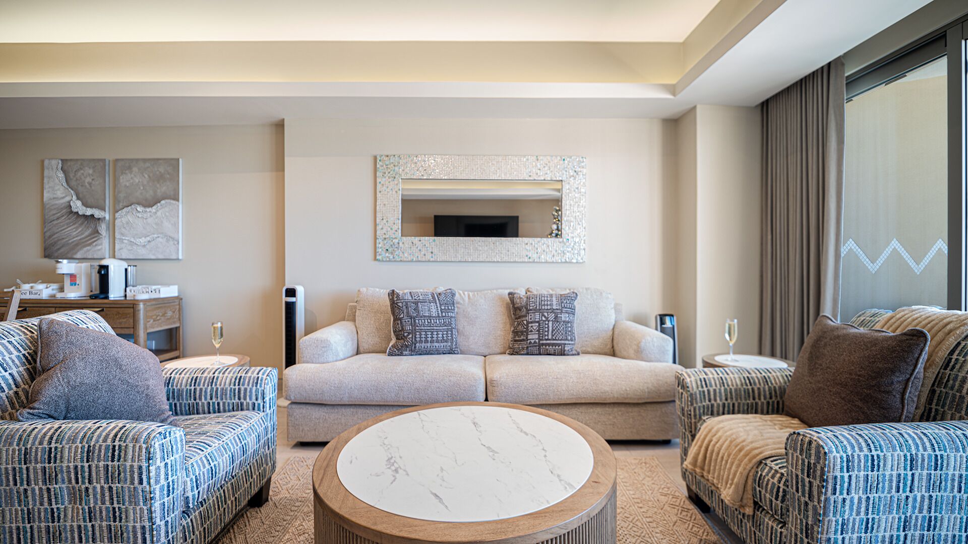 A modern living room with a sofa set, a coffee table, and a large mirror on the wall.
