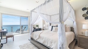A bedroom with a four-poster canopy bed, a balcony with a view of the sea, and a desk with a chair. - One 1502 – Modern Seaside Retreat Boasting Unforgettable Scenery (Puerto Peñasco)