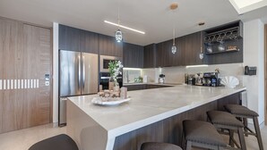 A modern kitchen with a large island, stainless steel appliances, and bar seating. - One 1502 – Modern Seaside Retreat Boasting Unforgettable Scenery (Puerto Peñasco)