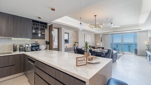 A modern kitchen with a marble countertop, built-in appliances, and a dining area with a view. - One 1502 Full– Beach Paradise with First-Class Comfort and Ocean Views (Puerto Peñasco)