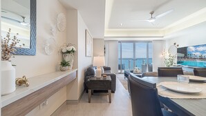 A modern living room with a dining area, large windows, and a view of the ocean. - One 1502 Full– Beach Paradise with First-Class Comfort and Ocean Views (Puerto Peñasco)