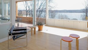 Um interior moderno com uma janela grande, uma cadeira preta, uma mesa pequena e um vaso de planta.