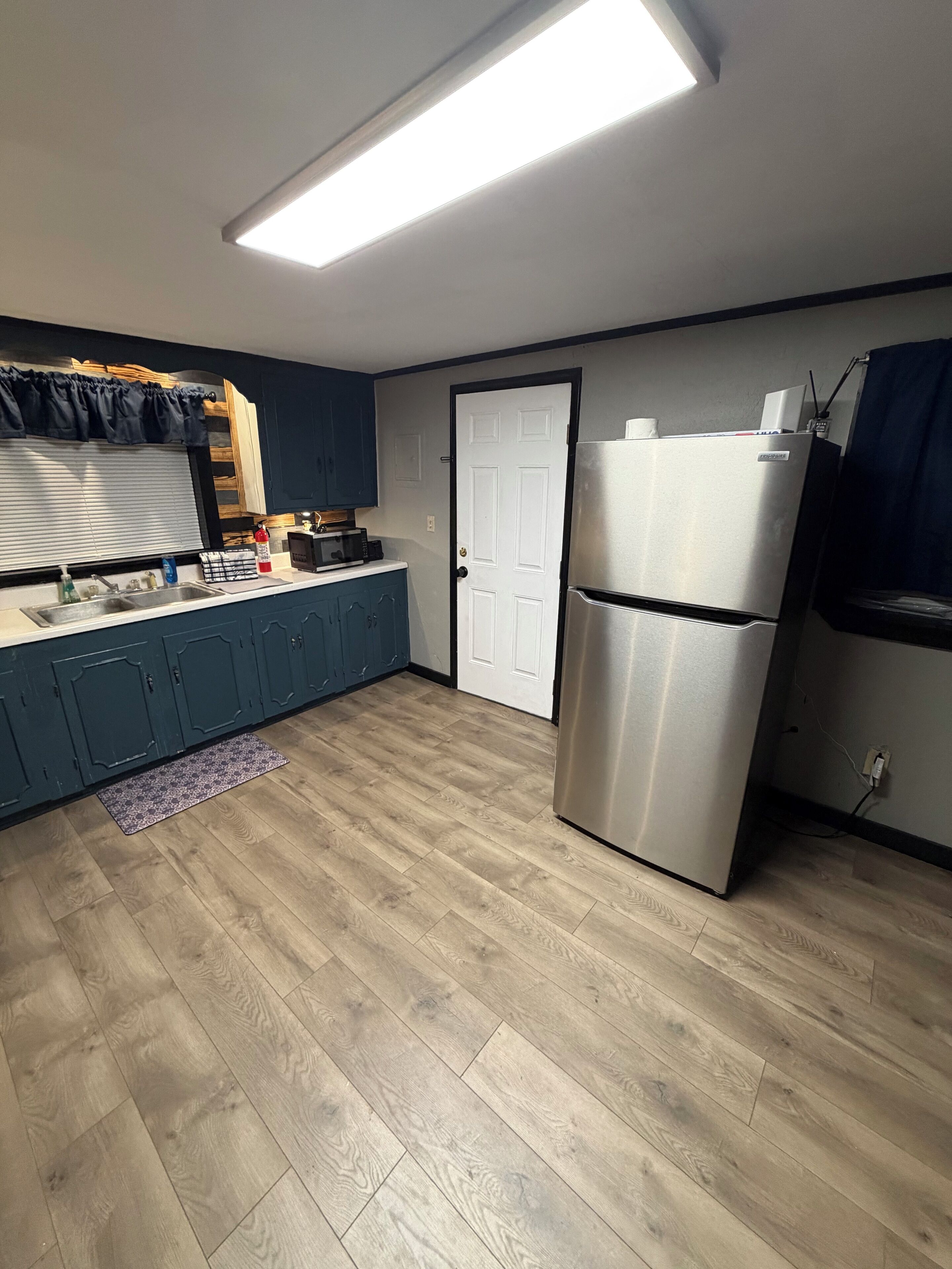 A kitchen with a refrigerator, microwave, and wooden cabinets.