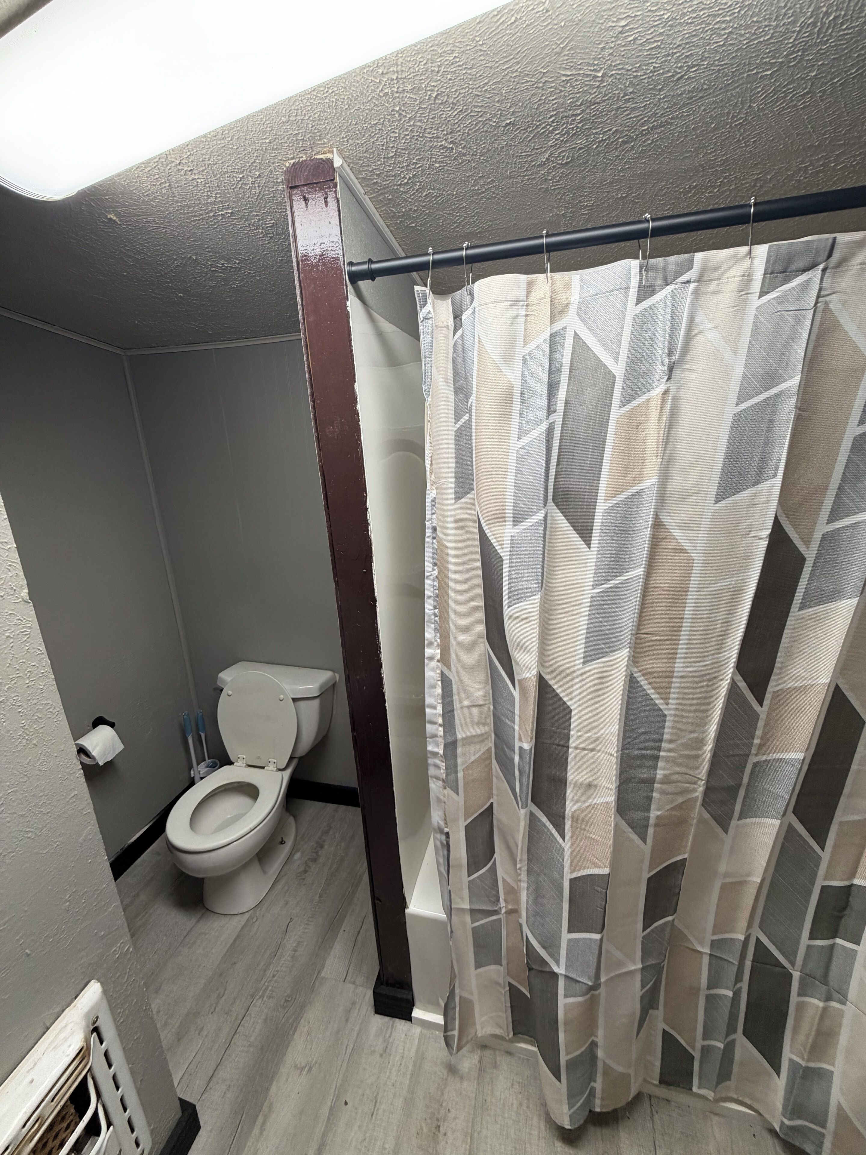 A bathroom with a toilet, a shower curtain, and a towel rack.