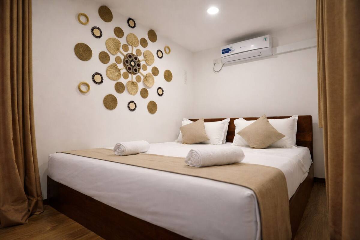 Et hotelværelse med en pænt redt seng, en billeddekoration og en aircondition.
