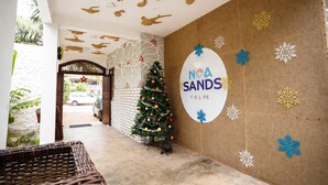 A hotel entrance with a Christmas tree, a wall with snowflake decorations, and a ceiling with sun and crab designs. - Noa Sands Talpe  by Ceylon Vistas (Talpe)