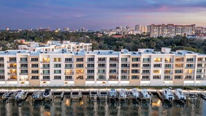 Een modern hotel met meerdere verdiepingen, een jachthaven met boten en een stadsachtergrond.