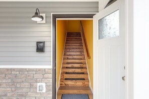 Eine Holztreppe mit einer gelben Wand und einer weißen Tür am Fuß.