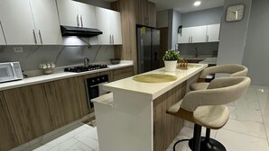 Eine moderne Küche mit Kochinsel, Barhocker und integriertem Kühlschrank.