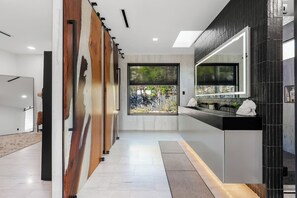 A modern kitchen with a large window, a black countertop, and a mirrored backsplash. - Modern Hilltop Retreat with Pool Near Downtown (Austin)
