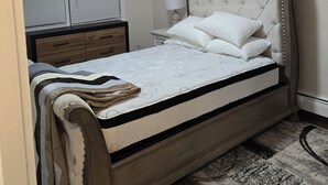 Une chambre à coucher avec un lit, une table de chevet, une lampe et un luminaire au plafond.