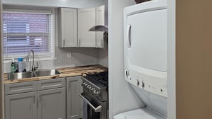 Une cuisine équipée d’une cuisinière, d’un four, d’un évier et de meubles blancs.