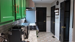 Een keuken met groene kastjes, een fornuis, een spoelbak en een magnetron.