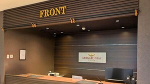A reception desk with a sign that reads "FRONT" and "ARIGATO STAY SUZUKA". - Hotel Trend Suzuka (Suzuka)