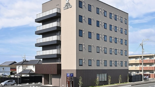 A modern hotel building with a flat roof, multiple balconies, and a sign indicating a parking area. - Hotel Trend Suzuka (Suzuka)